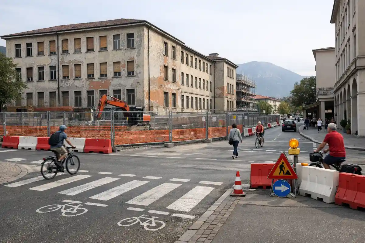 Vecchio edificio recintato con escavatore, attraversamento ciclopedonale e barriere stradali con ciclisti e pedoni